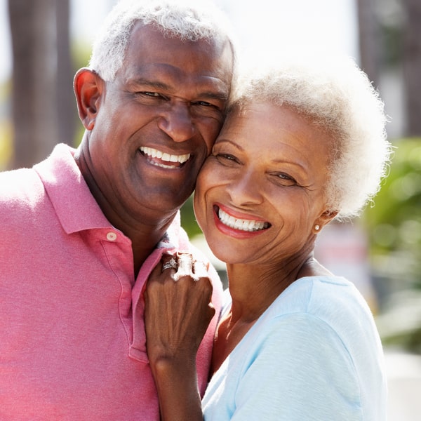 elderly-couple-hugging-and-smiling-in-a-park