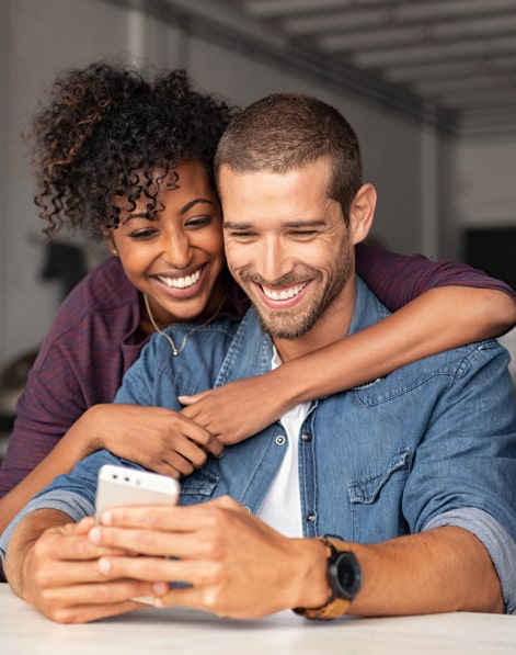 Couple-hugging-and-smiling-while-looking-at-iPhone